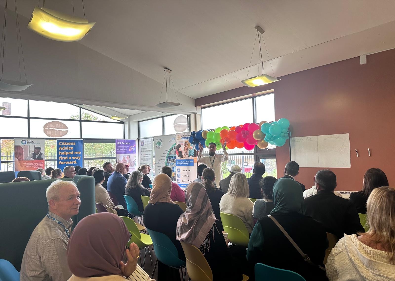 A gathering at the launch of Chat & Chai with colourful balloons and local support displays.