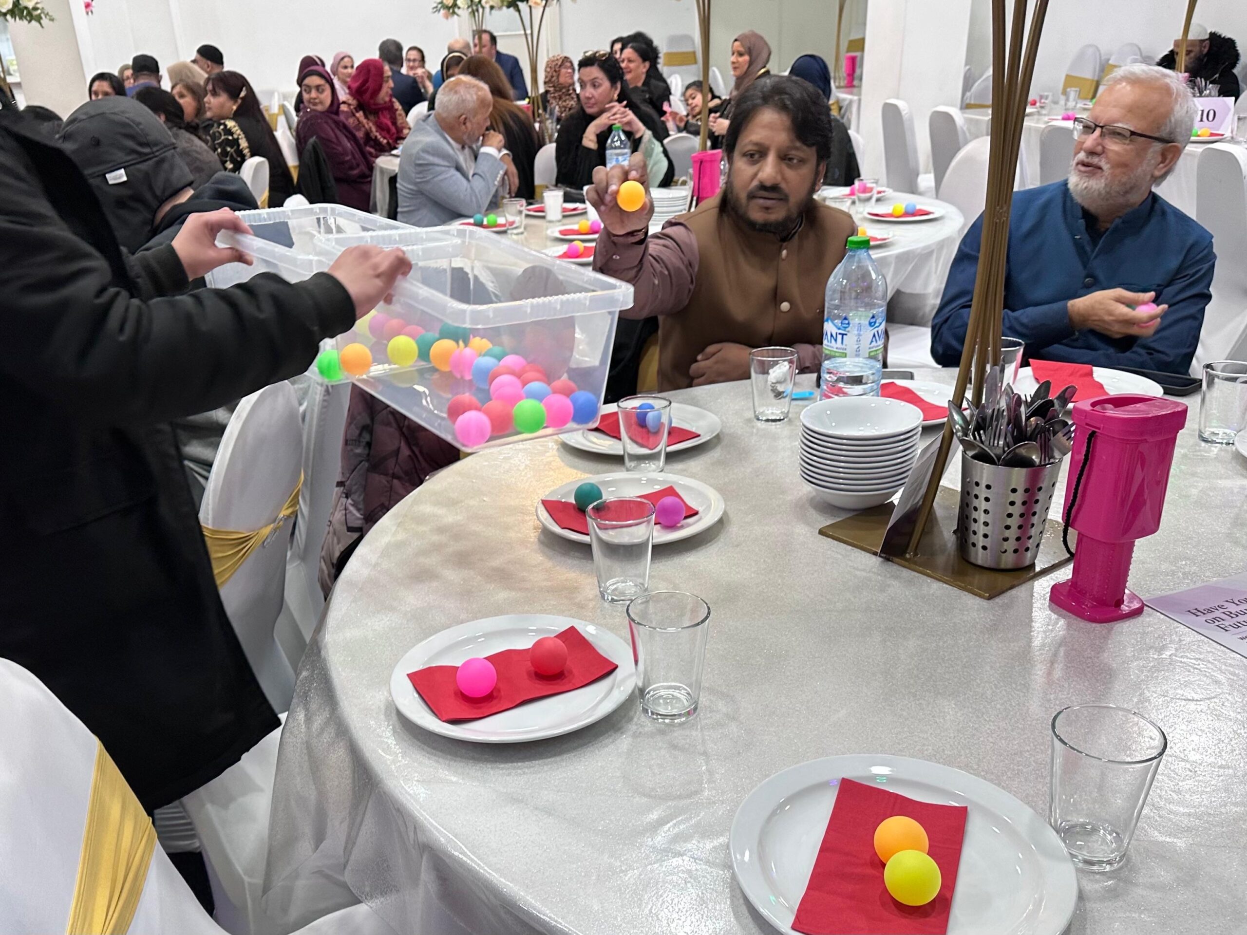 People taking part in a community consultation activity around tables, using coloured balls.